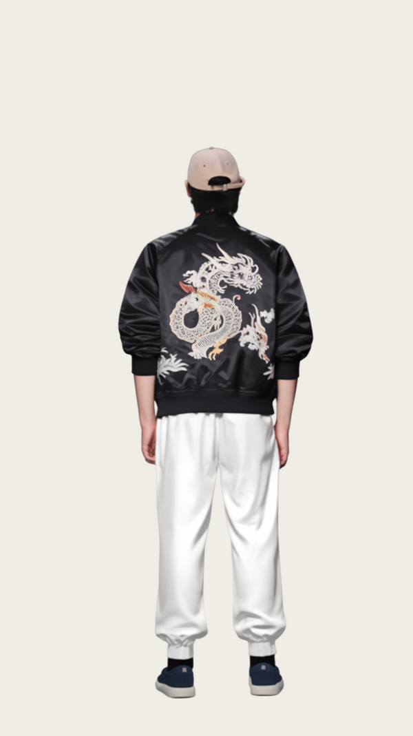 Person wearing a black jacket with a dragon design on the back against a gray background