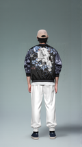 Person wearing a black jacket with white designs on a gray background