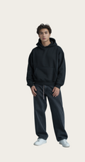 Person wearing a black hoodie and dark pants on a gray background
