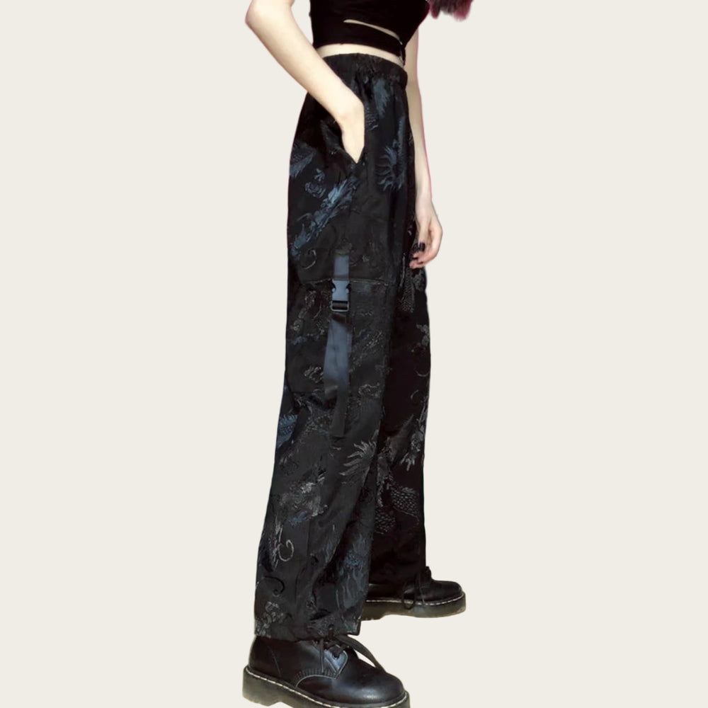 Person wearing black floral pants and black shoes in a room with colorful walls.
