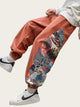 Person wearing orange pants with a colorful design and white sneakers on a gray background
