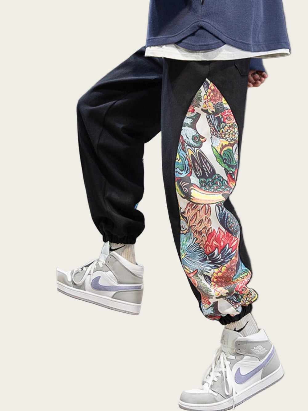 Person wearing colorful pants with a floral design, standing next to a skateboard indoors.