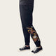 Black jogger pants with colorful dragon embroidery worn by a person on a white background