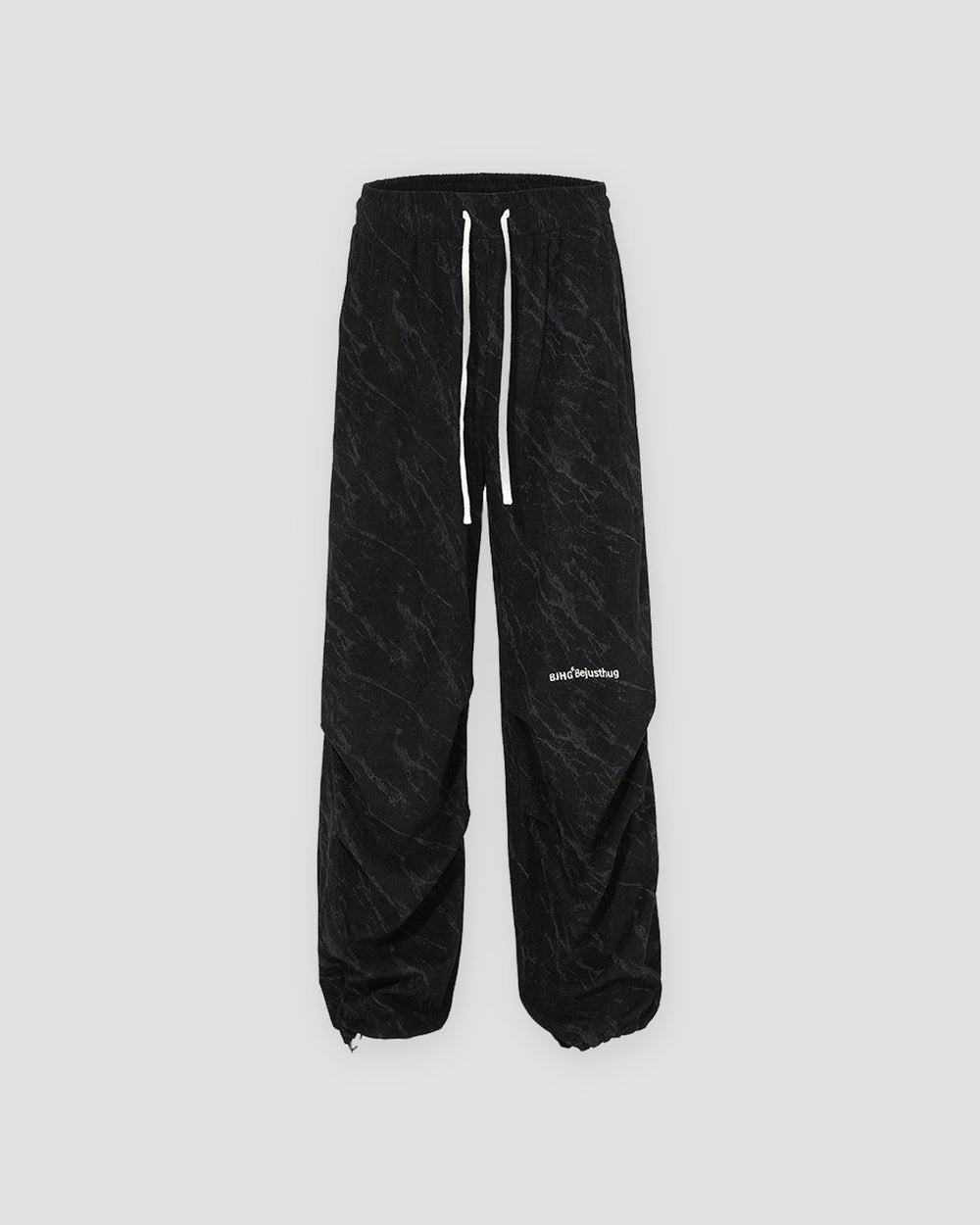 Black acid-wash corduroy parachute pants with a drawstring hem, front view
