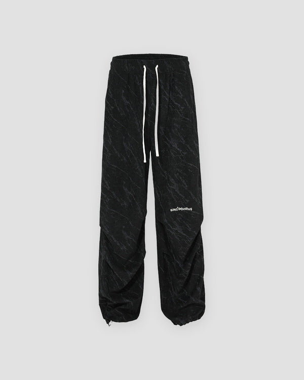Black acid-wash corduroy parachute pants with a drawstring hem, front view