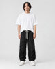 Model wearing the black acid-wash corduroy parachute pants with a white tee, front view