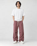 Model wearing the pink acid-wash corduroy parachute pants, front view