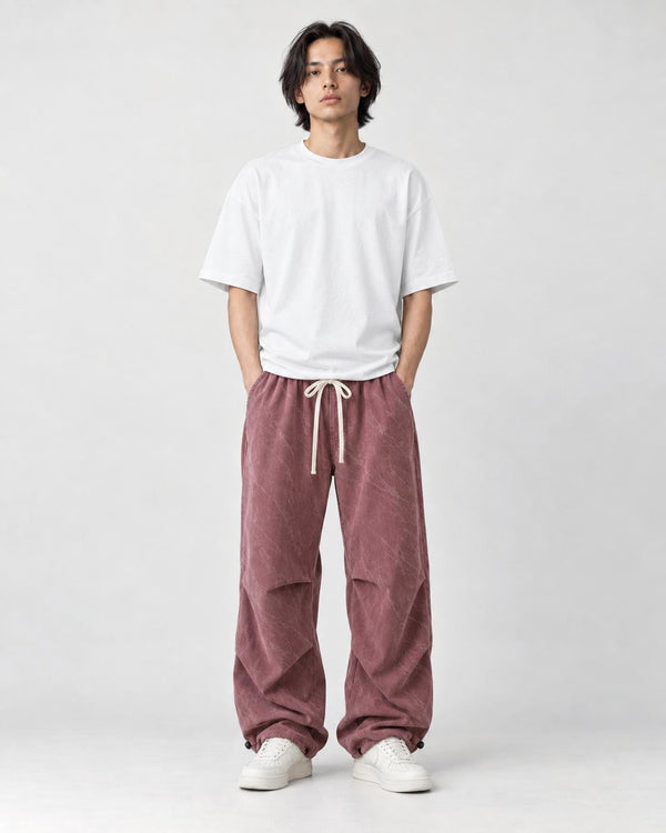 Model wearing the pink acid-wash corduroy parachute pants, front view