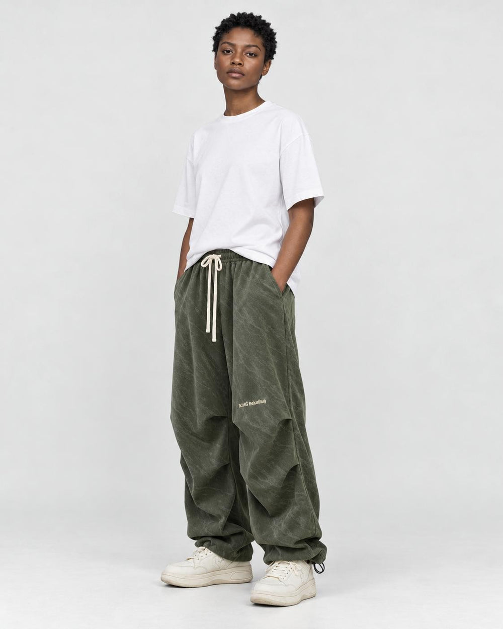 Model wearing the olive green corduroy parachute pants, three-quarter view