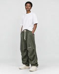 Model wearing the olive green corduroy parachute pants, three-quarter view