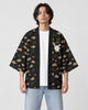 Man in the open black cloud-pattern haori with a small white cat emblem on the chest, a white tee and light jeans