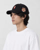 Man wearing the black baseball cap in profile, showing the embroidered lion-dance head on the side