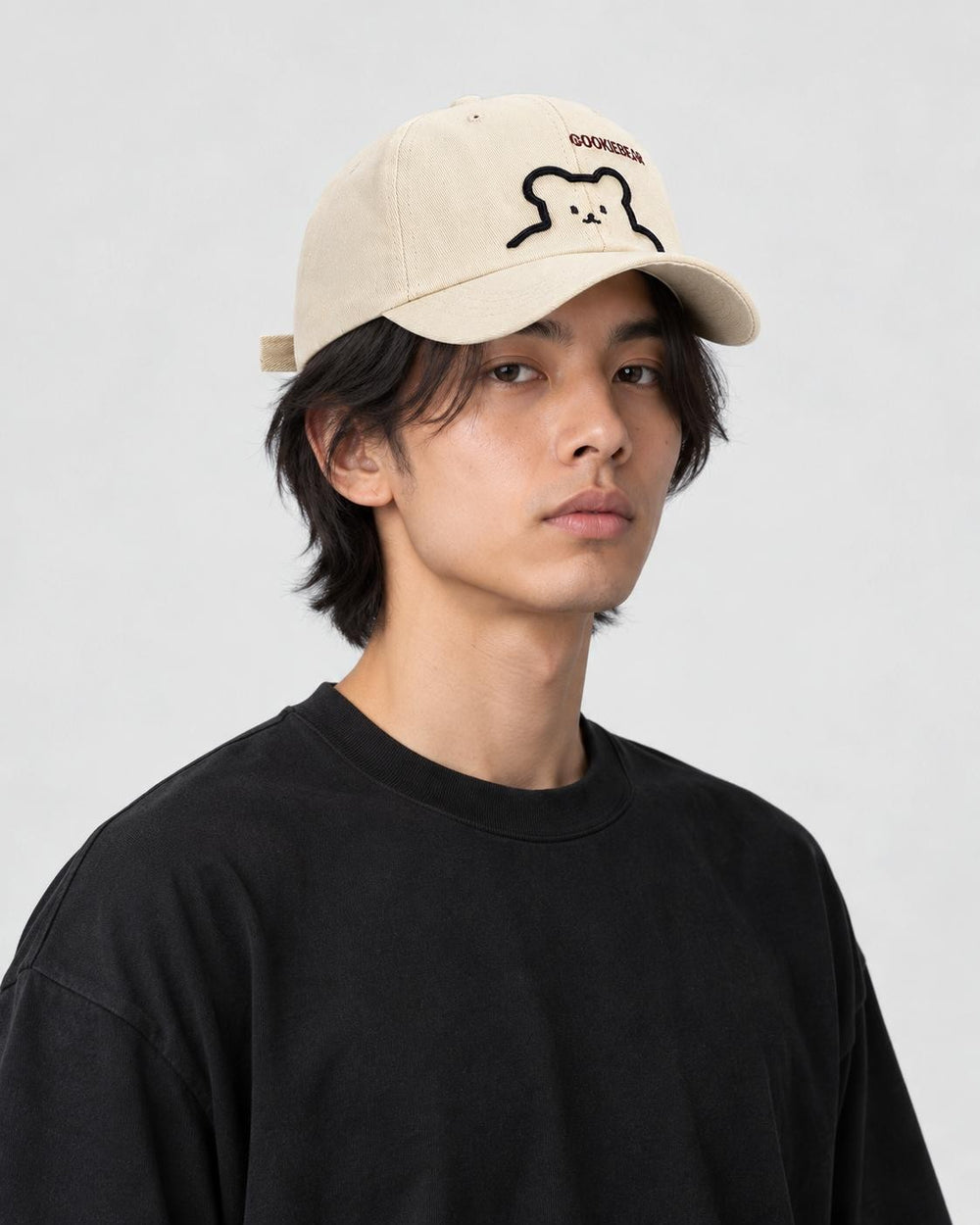 Model wearing the cream bear baseball cap with a black tee, three-quarter view