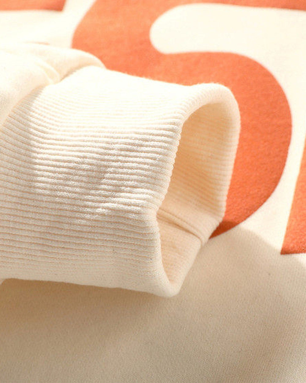 Close-up of the ribbed cuff and the printed letter on the sleeve