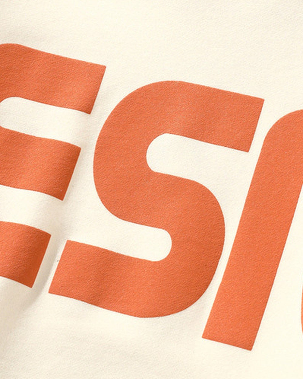 Close-up of the raised orange block letters on the cream sweatshirt