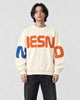 Model wearing the cream sweatshirt with orange block letters, front view