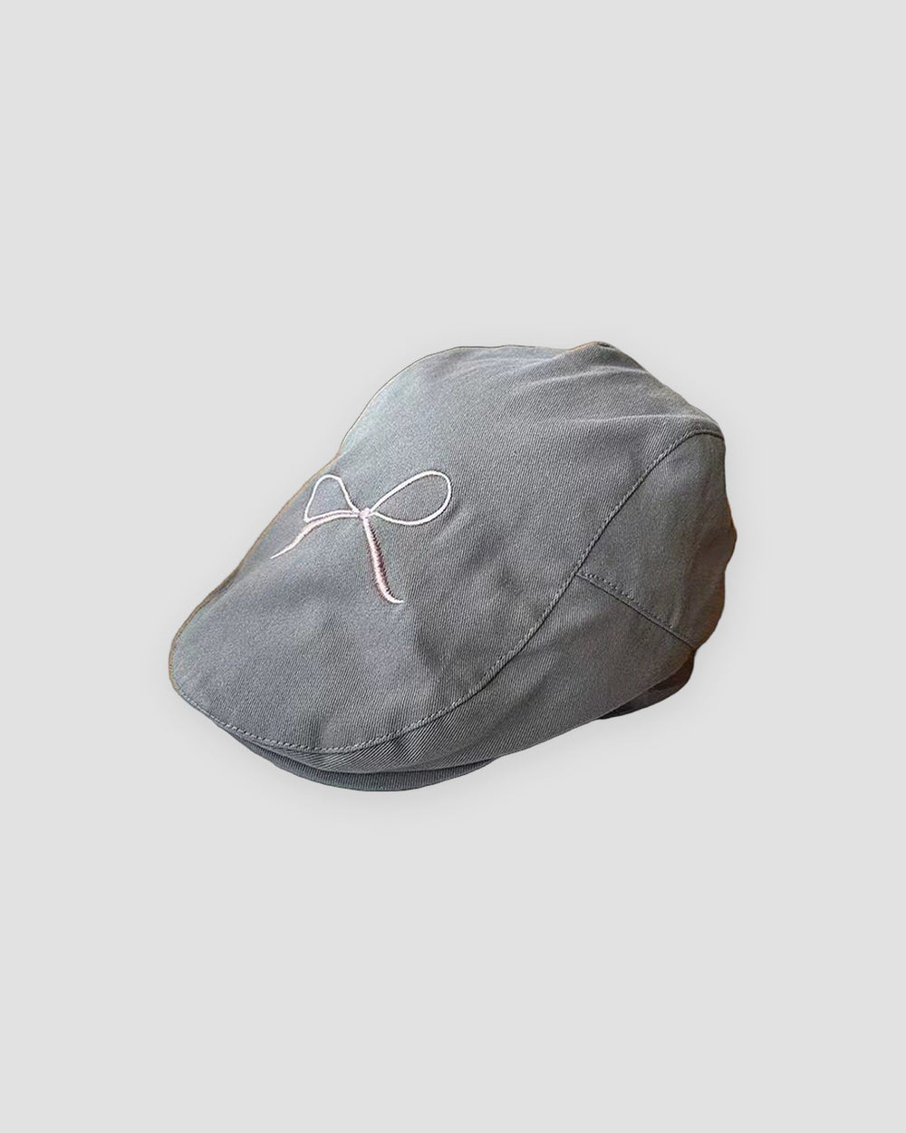 Gray flat cap with a fine pale pink bow embroidered on the crown