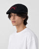 Model wearing the black bow embroidered flat cap with a white tee, side view