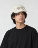 Model wearing the cream bow embroidered flat cap with a black tee, three-quarter view