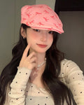 Woman in the pink bow print flat cap with her hand at her cheek, showing the short rounded peak