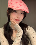 Pink bow print flat cap worn straight, with the curved side seam of the crown visible