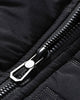 Close-up of the metal zip pull and the quilted fabric on the black jacket
