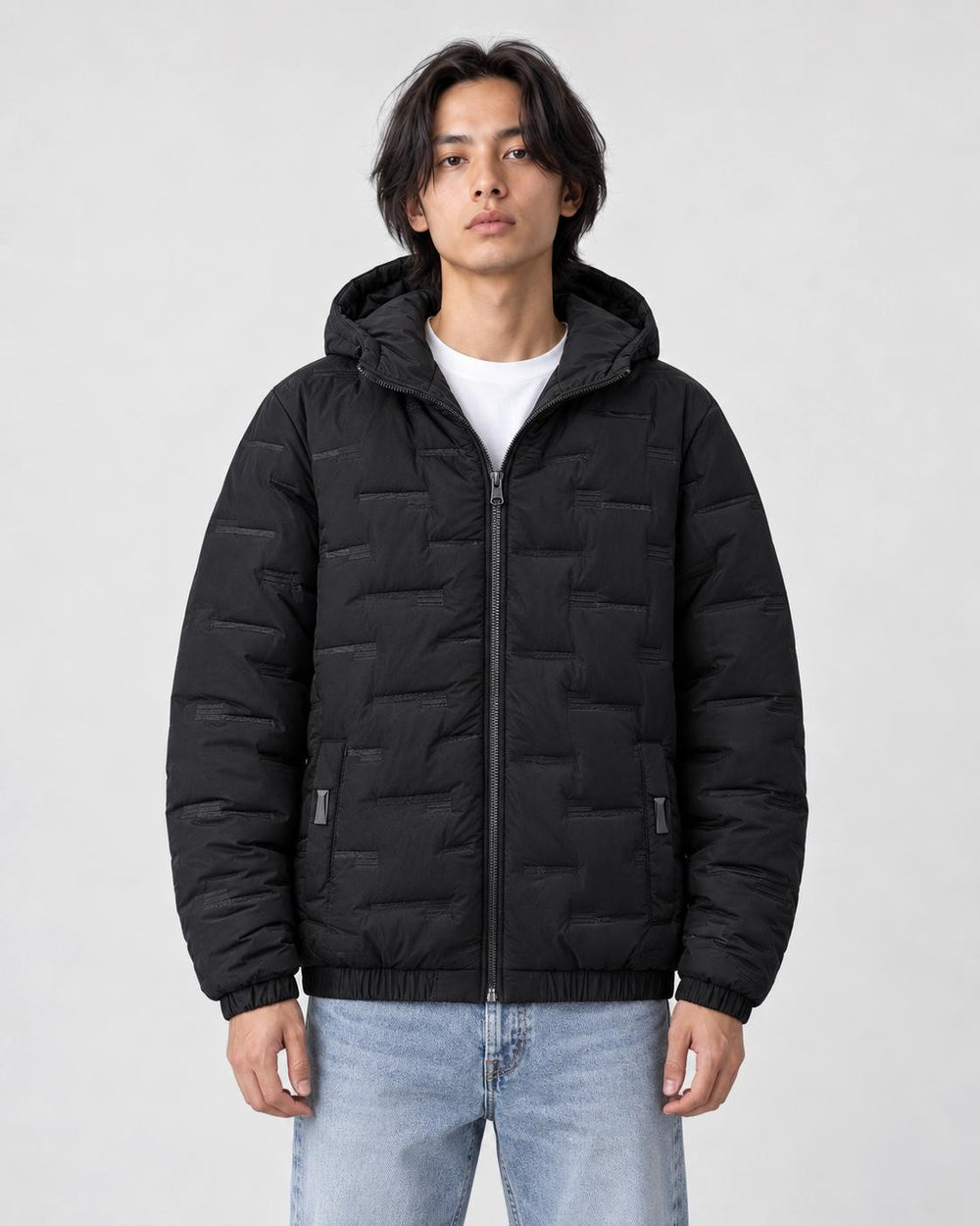 Model wearing the black quilted padded jacket zipped up over a white tee and light-wash jeans