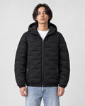Model wearing the black quilted padded jacket zipped up over a white tee and light-wash jeans
