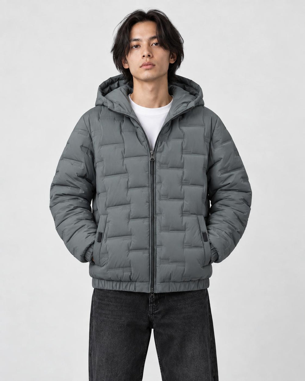 Model wearing the gray green quilted padded jacket zipped up over a white tee and black jeans