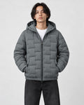 Model wearing the gray green quilted padded jacket zipped up over a white tee and black jeans