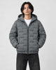 Model wearing the gray green quilted padded jacket zipped up over a white tee and black jeans