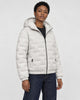 Model wearing the cream quilted padded jacket zipped up over a black tee, three-quarter view