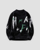 Black fuzzy knit sweater printed with white and green brushstroke letters