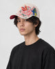 Model wearing the beige butterfly cap, side view of the embroidery