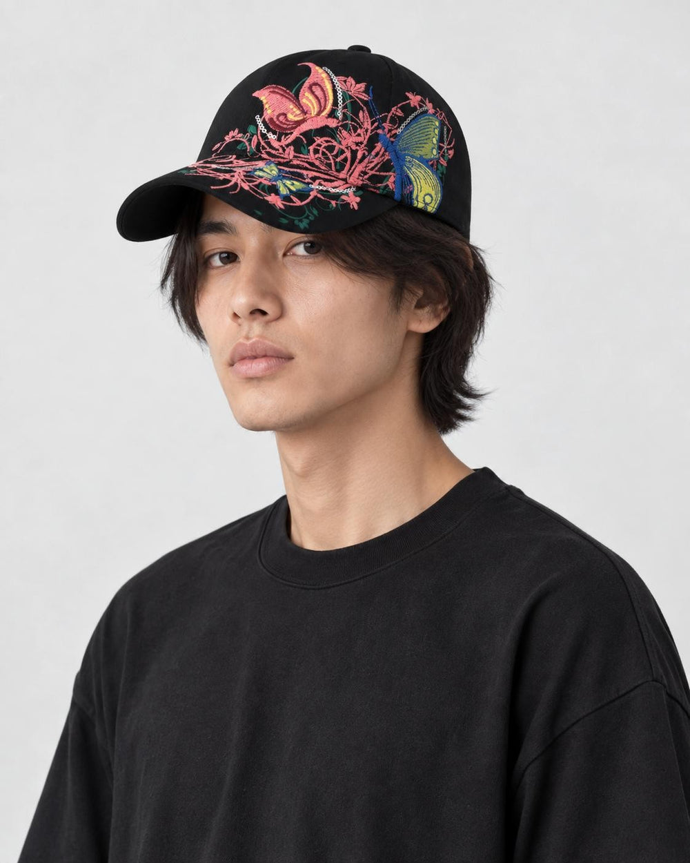 Model wearing the black butterfly embroidered cap, three-quarter view