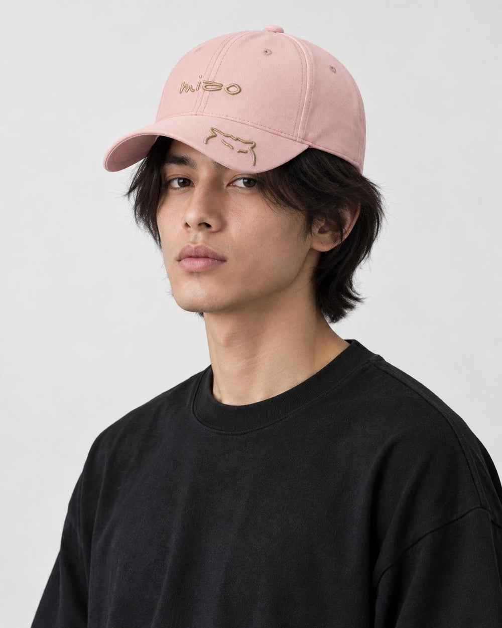 Model wearing the pink mizo cat embroidered baseball cap with a black tee, three-quarter view