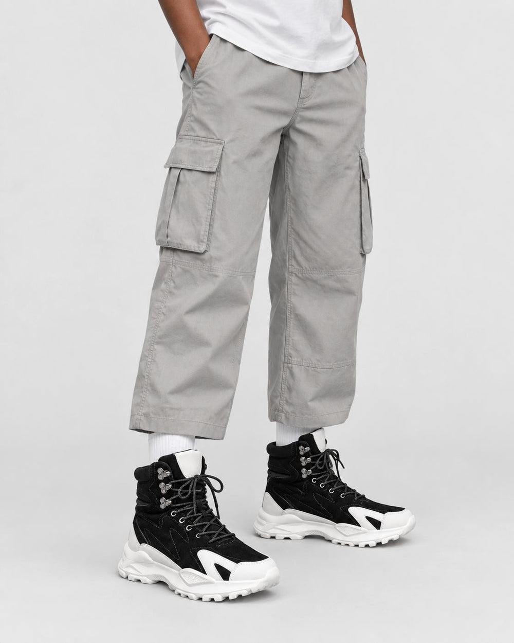 Model wearing the black high-top sneakers with stone cargo trousers, front view
