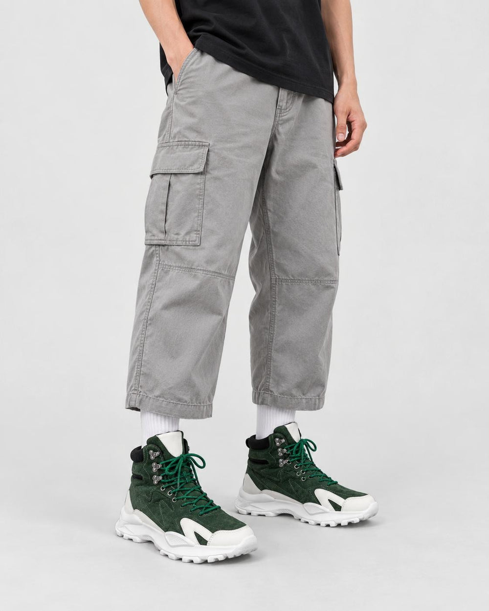 Model wearing the green high-top sneakers with light gray cargo trousers, front view
