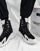 Black high-top sneakers worn with black cuffed pants, seen from the front