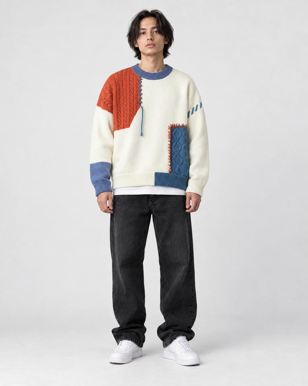Model wearing the orange and blue cable patch sweater with jeans, front view