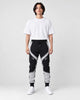 Model wearing the black color block jogger pants with gray panels and a white tee, front view