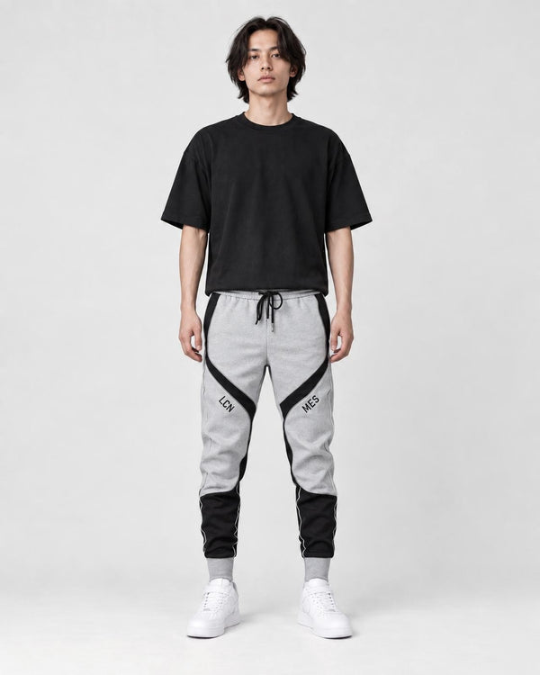 Model wearing the gray color block jogger pants with a black tee, front view