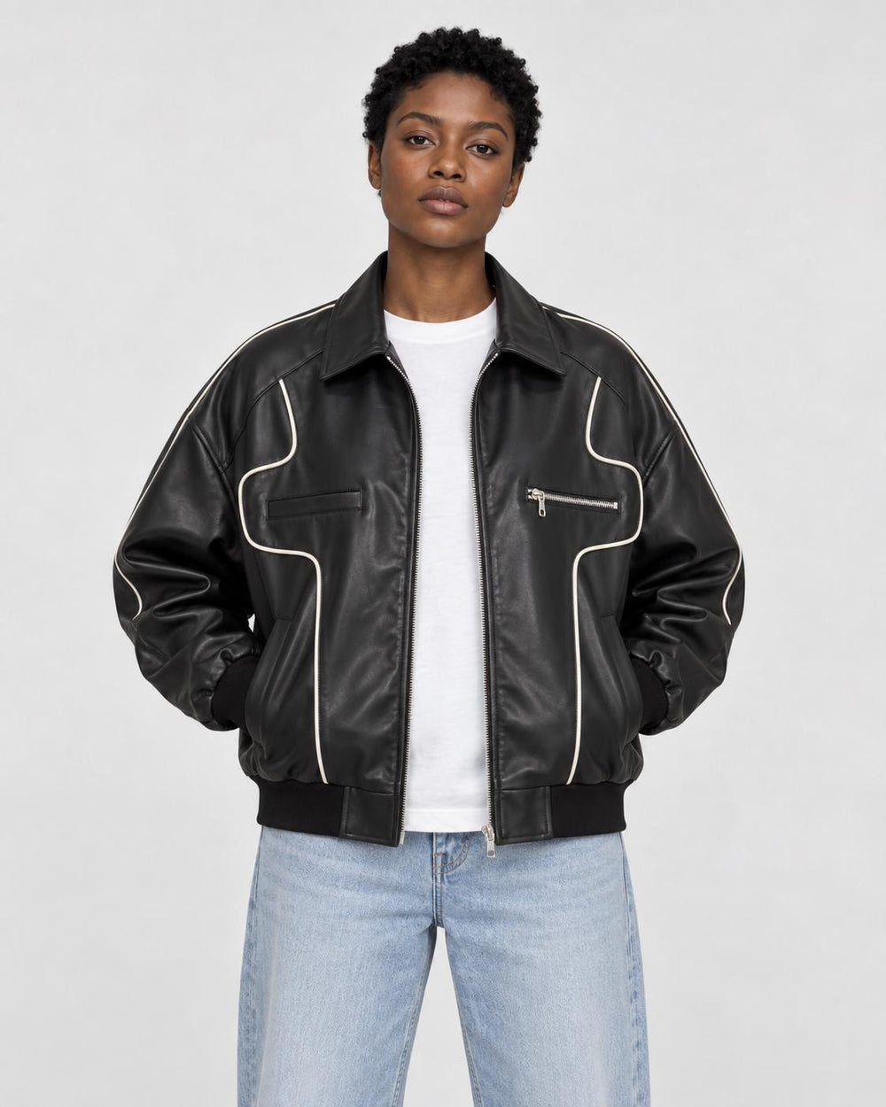 Model wearing the black PU leather zip jacket with white contour piping, front view