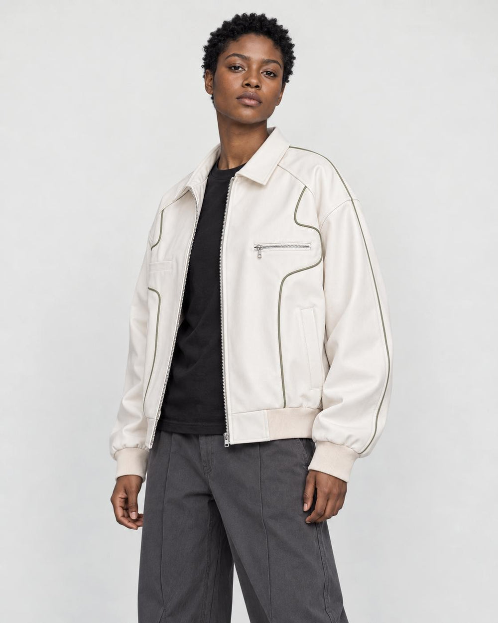 Model wearing the white piped PU leather jacket open over a black tee, three-quarter view