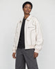 Model wearing the white piped PU leather jacket open over a black tee, three-quarter view