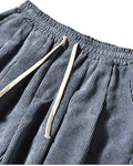 Close-up of the elastic waist, cream drawcord and pocket on the blue gray corduroy pants