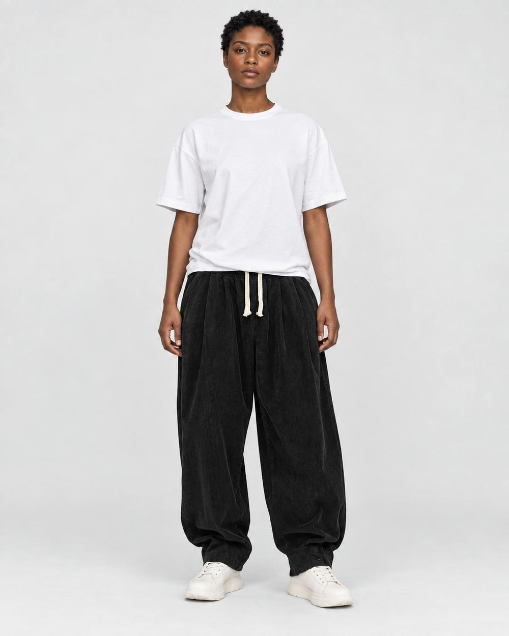 Model wearing the black corduroy lantern pants with a white tee, front view