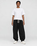 Model wearing the black corduroy lantern pants with a white tee, front view