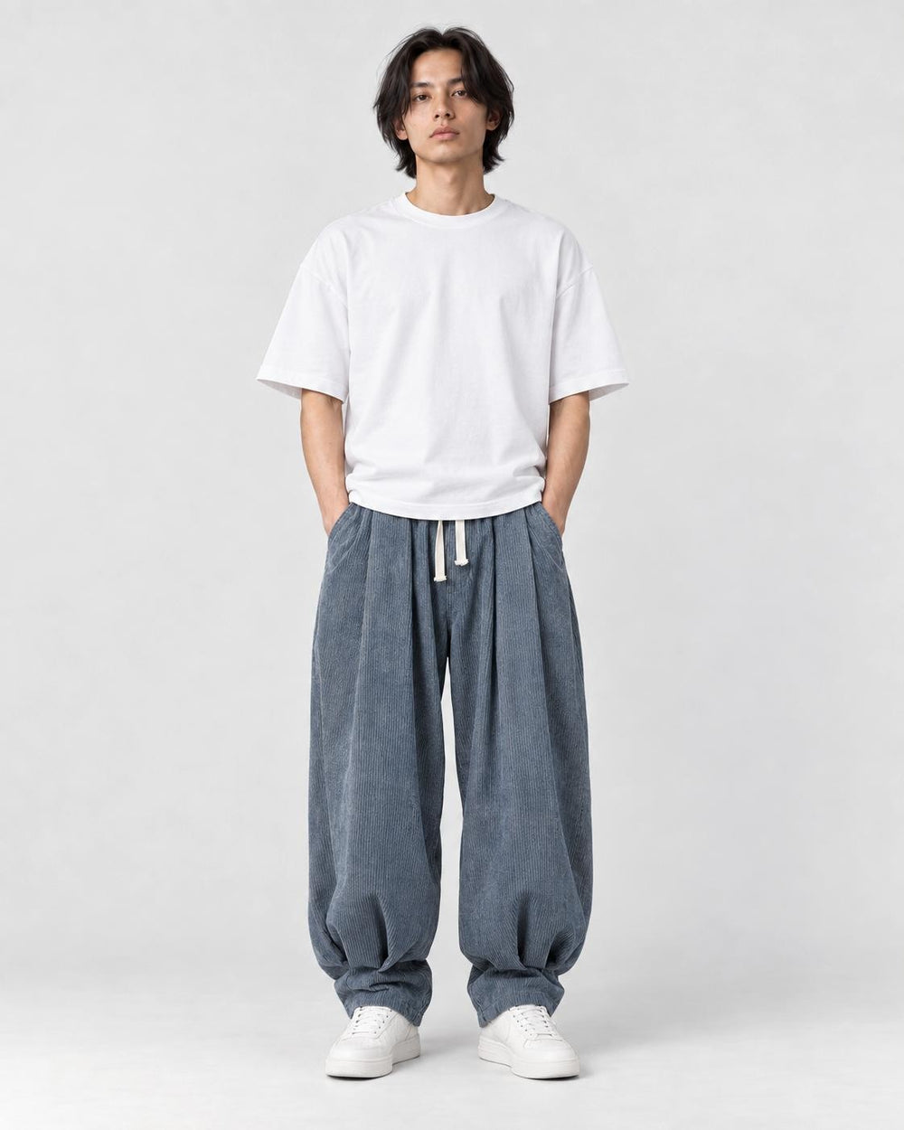 Model wearing the blue gray corduroy lantern pants with a white tee, front view