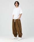 Model wearing the brown corduroy lantern pants with a white tee, three-quarter view